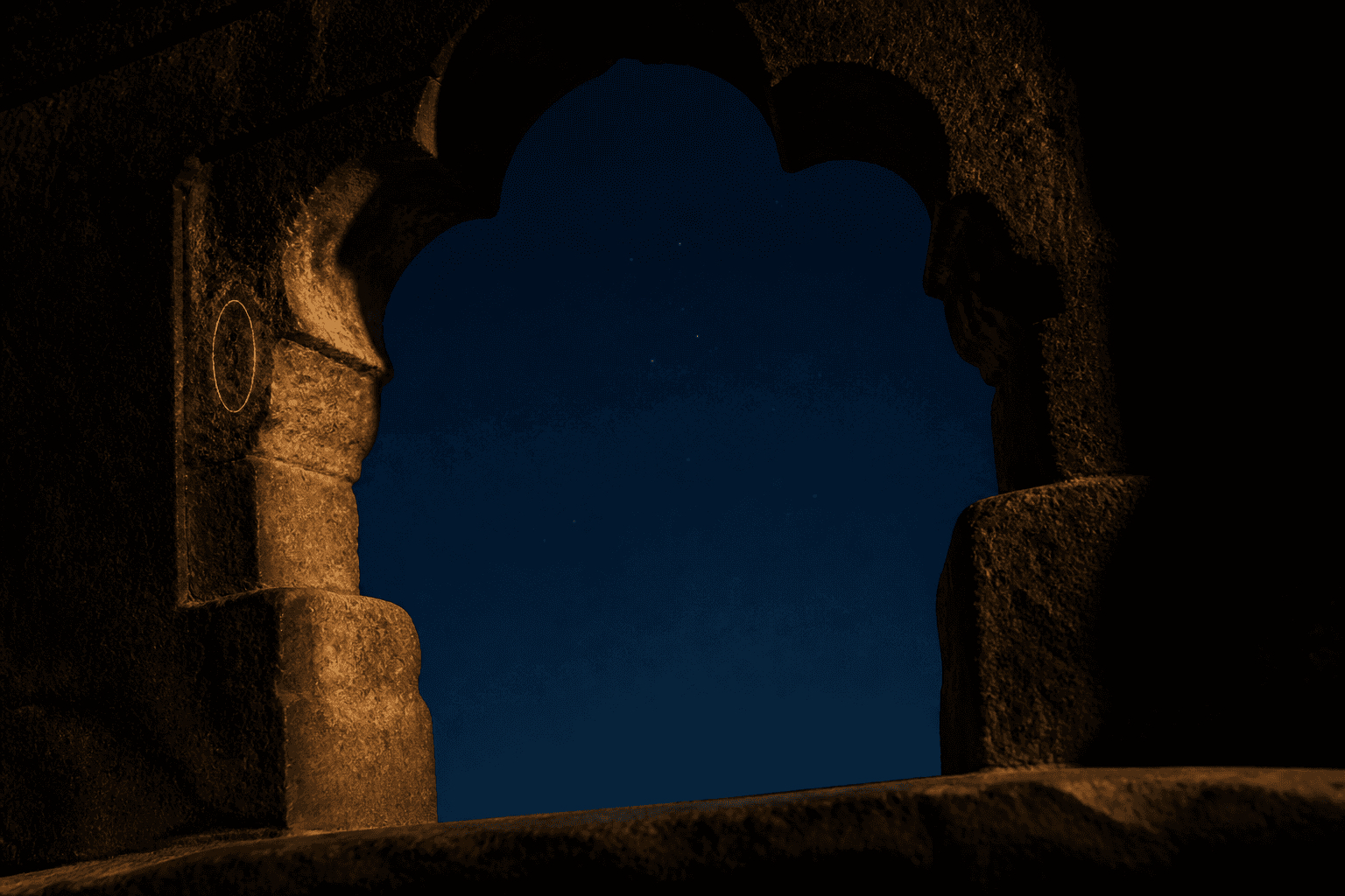 A still night sky seen through a carved temple arch, deep indigo shading to black with a faint dust of stars, the ether element of the Sacred Sandalwood attar